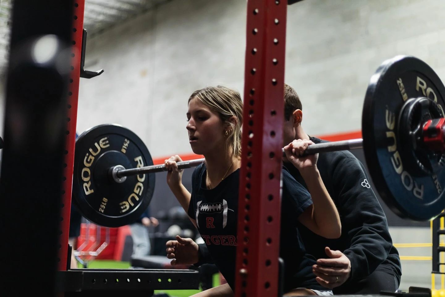 Matryx athlete performing a coached barbell squat under supervision on the training floor